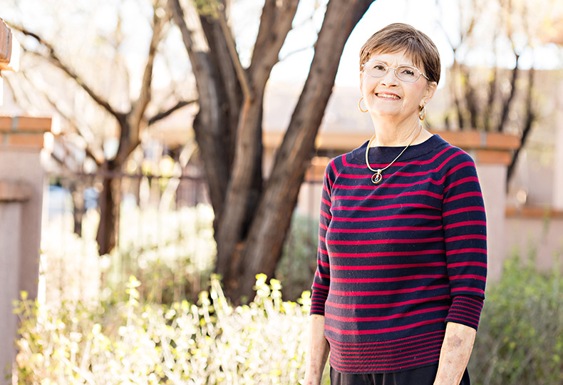 A resident is standing outside and smiling.