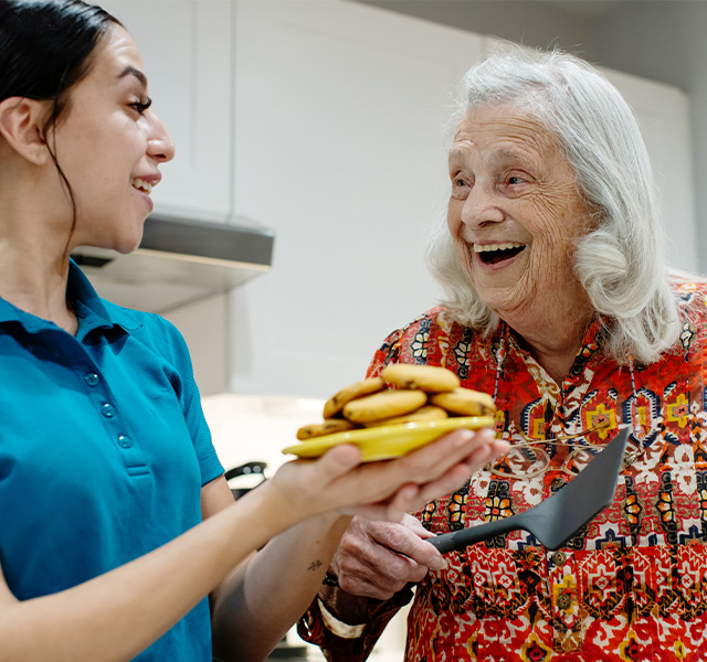 A resident and associate with a plate of cookies.