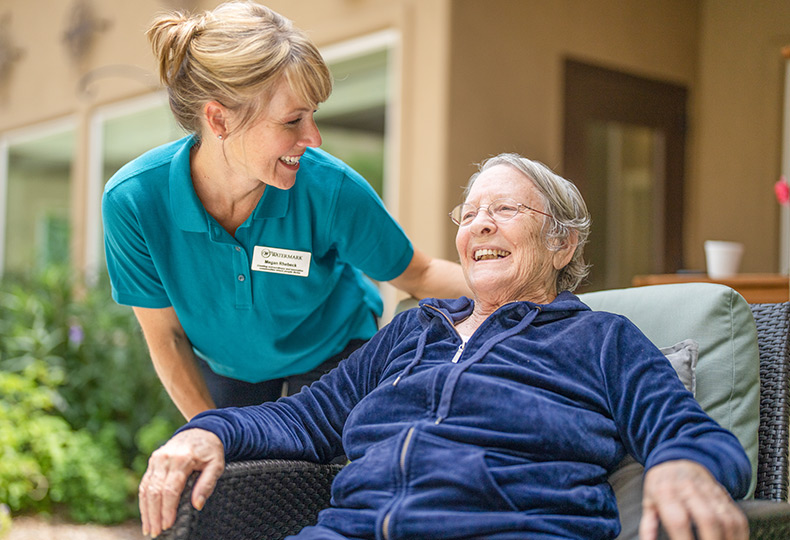 A resident is sitting outside with a caregiver.