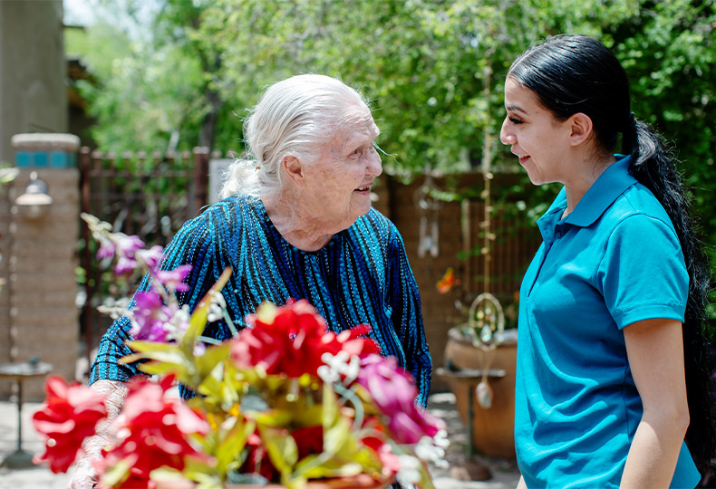 A person with a caregiver out in the courtyard garden.