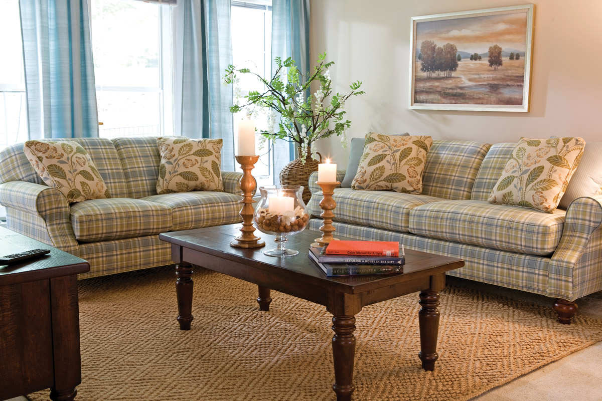 Furnished living room space with sofa, large window, coffee table, and arm chair.