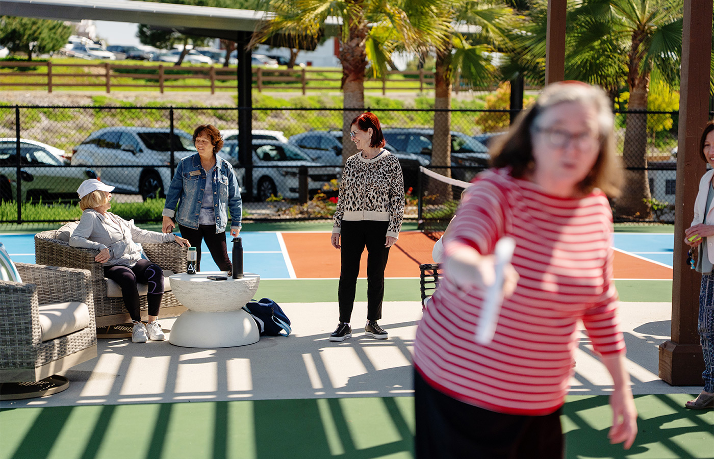 A person playing pickleball with others socializing in the back.