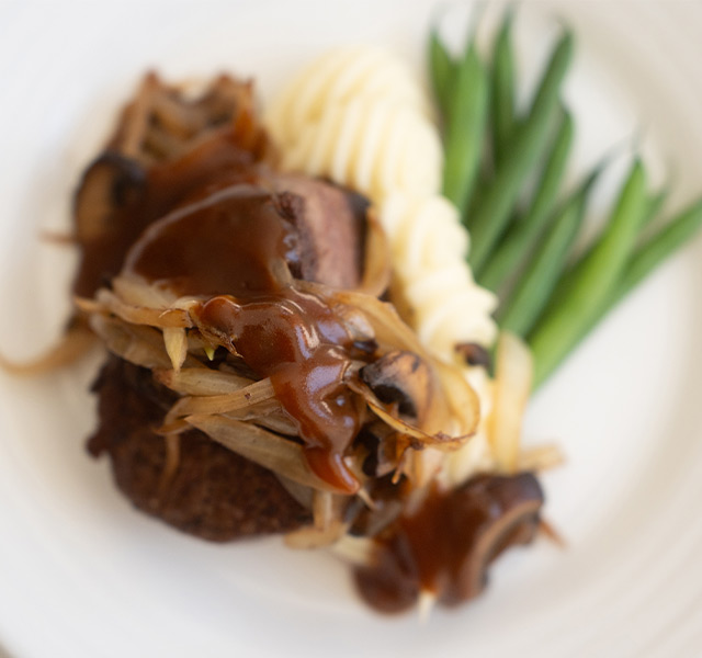 A plate with steak and green beans on it.