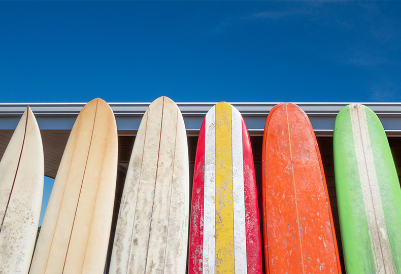A bunch of surf boards standing up.