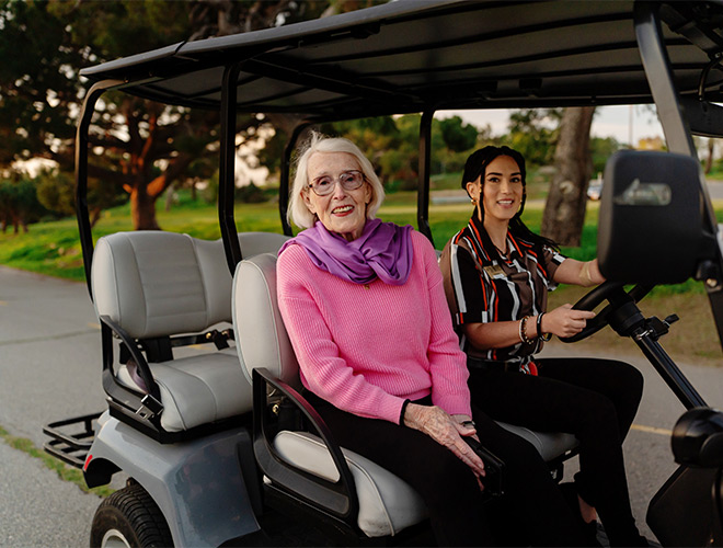 Two people on a golf cart.