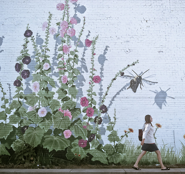 A person walking past a mural on a building.