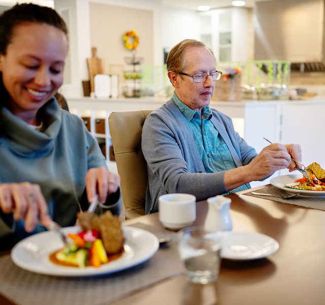 A resident eating dinner with a family member.
