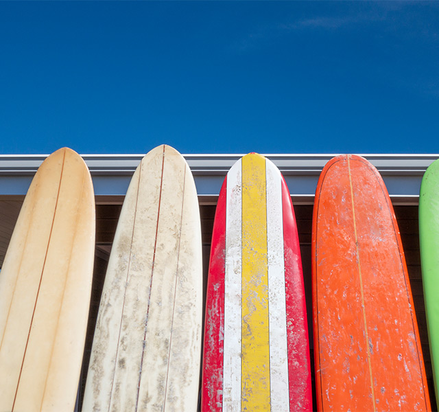 A bunch of surf boards up against a building.