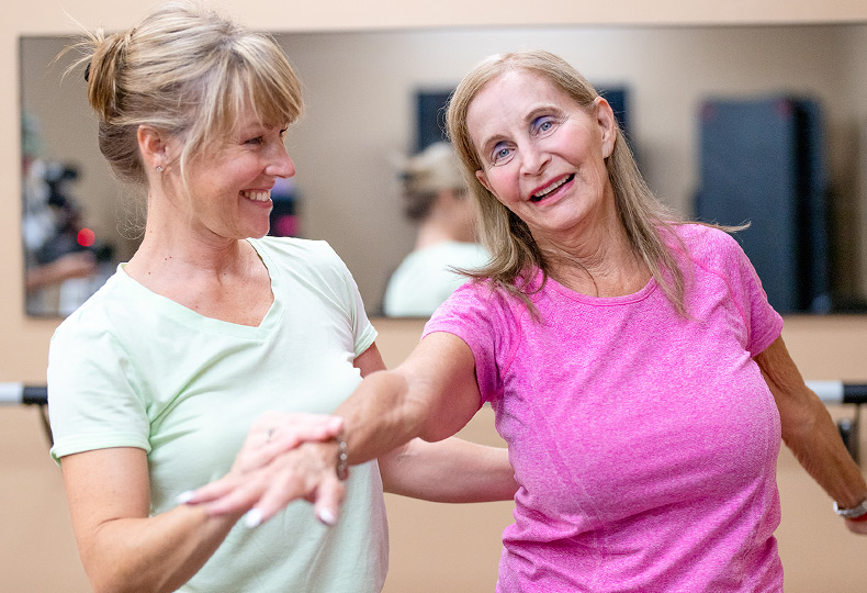 A caregiver is helping a resident stretch their arm.