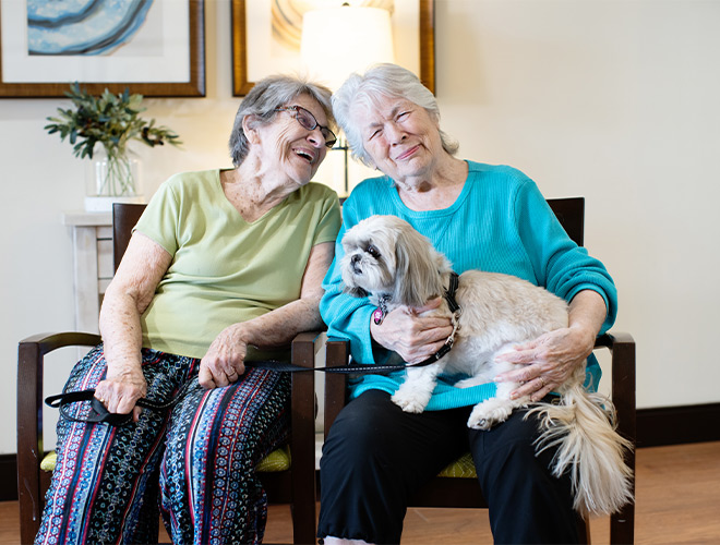 Two people sitting with a dog.