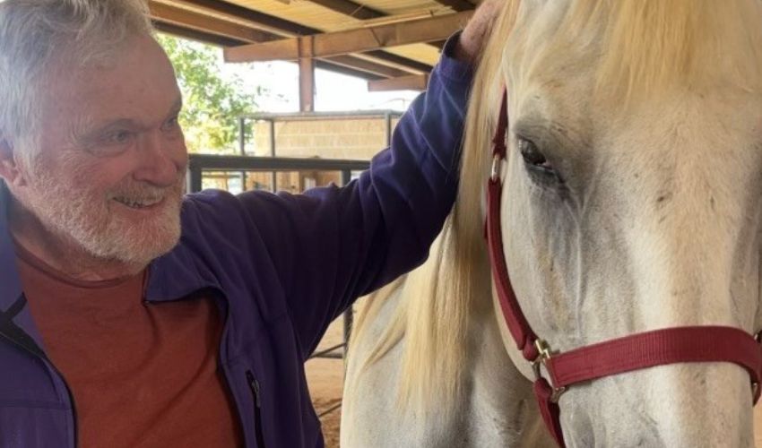 A man is petting a horse.