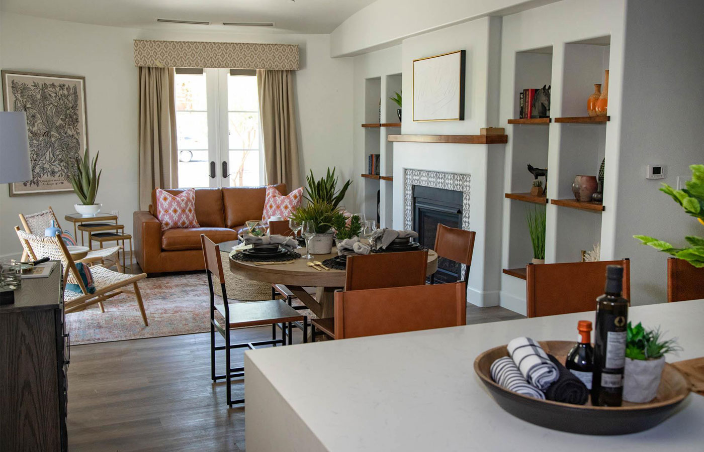 A bright living room with leather furniture and a wood burning fireplace.