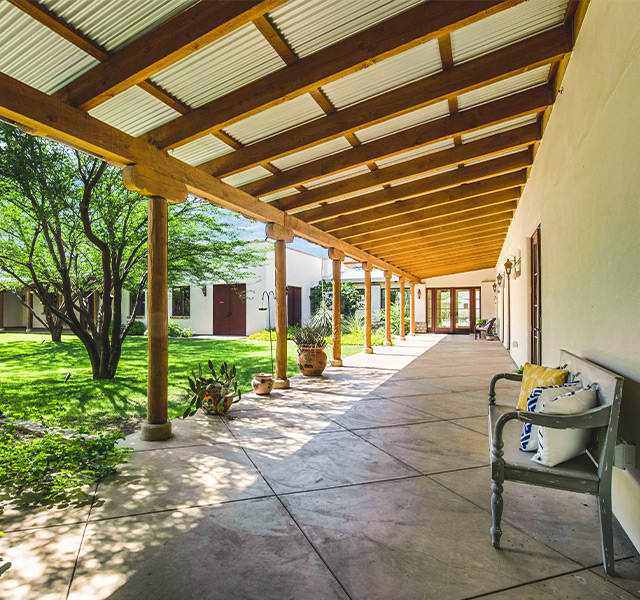 A porch with a bench and pillows for sitting.