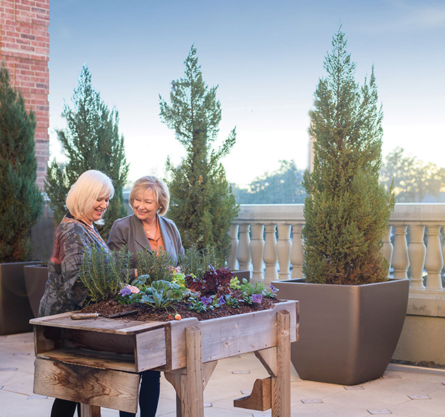 Two residents outside smiling and gardening.