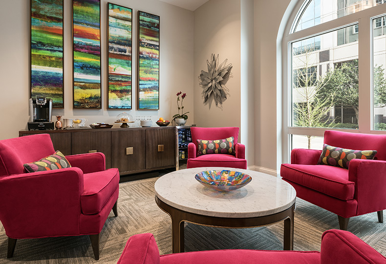 Lounge area with red plush chairs and a small round table.