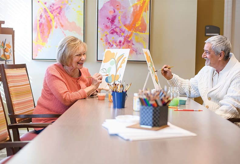 Residents enjoying an art class with canvases and paint brushes.