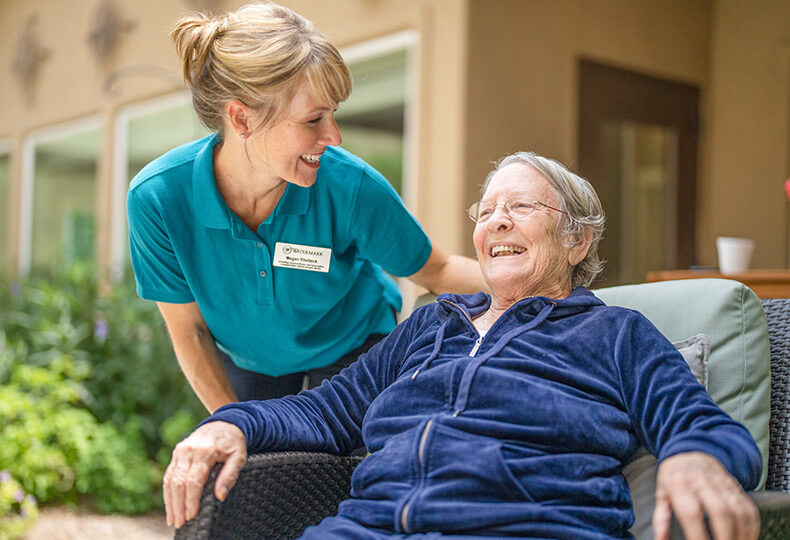 A smiling resident with their caregiver.
