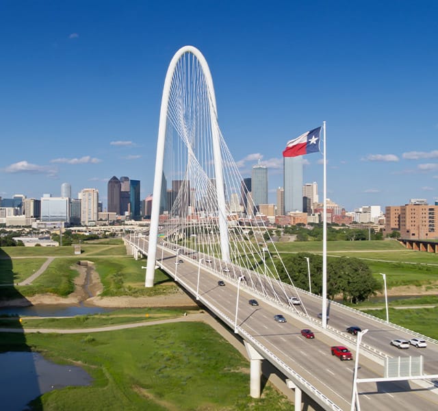 Aerial shot of Dallas, Texas, looking along the Margaret Hunt Hill and Roland Kirk bridges crossing the Trinity River into downtown Dallas on a sunny day in summer.
