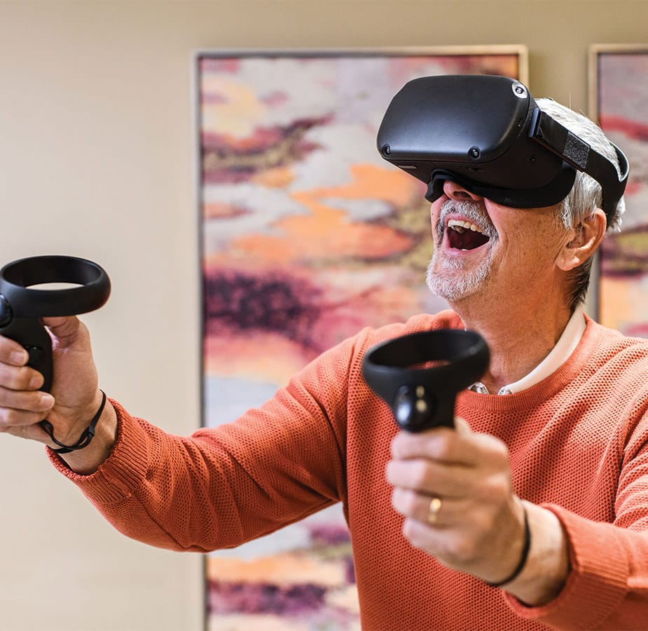 Resident enjoying virtual reality wearing goggles and holding controls.