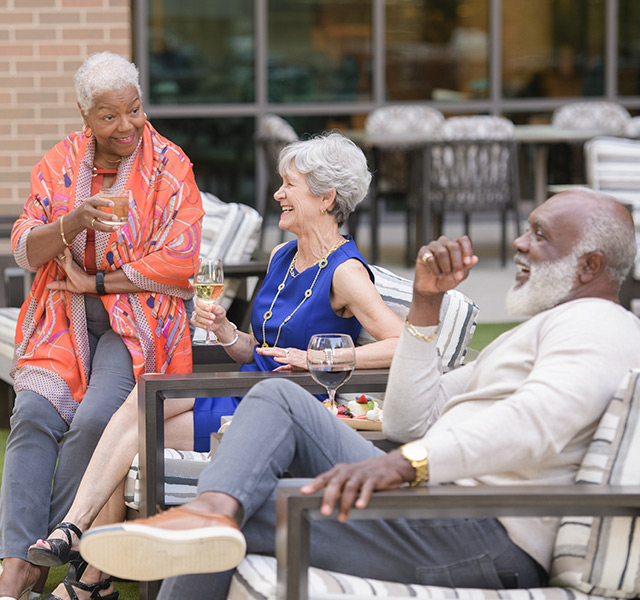 three residents sitting outside laughing 