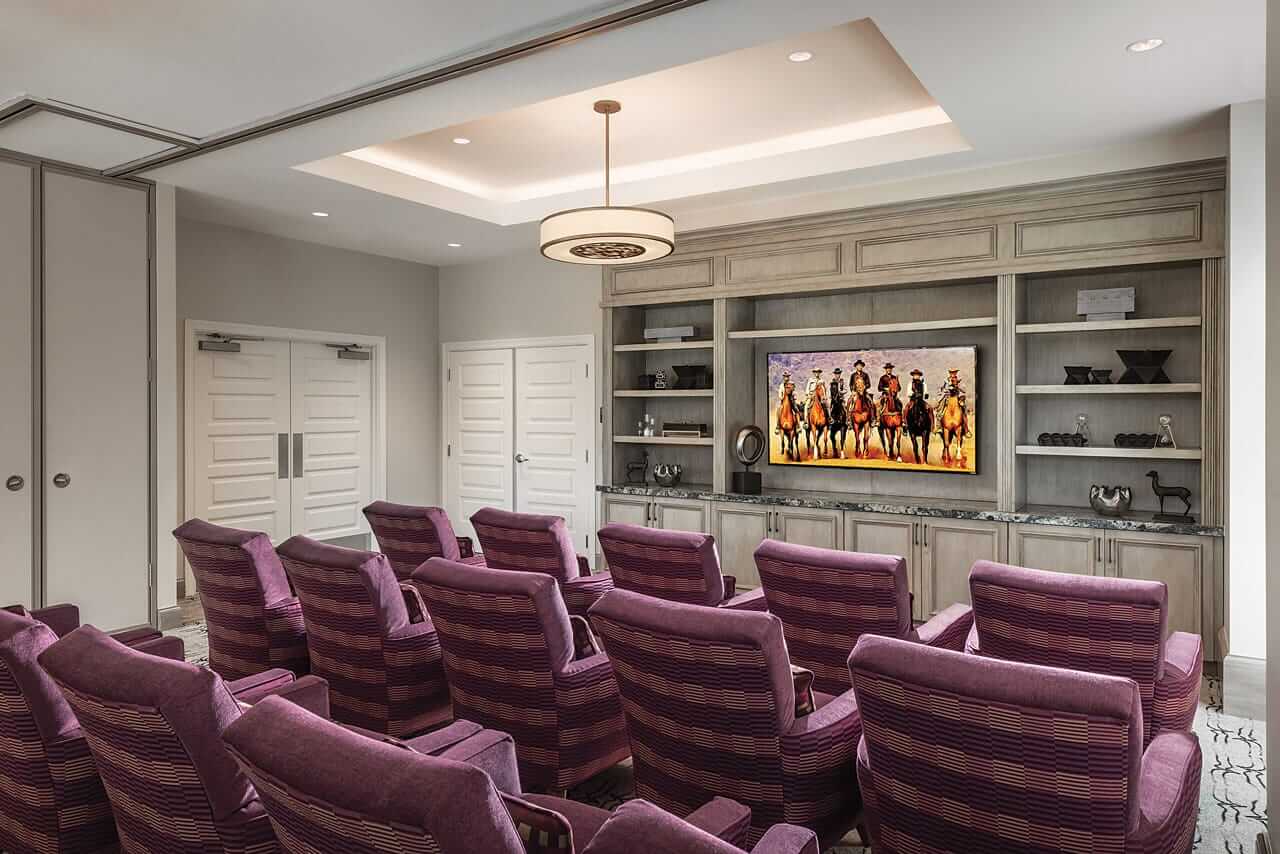 a room with seating lined up and facing a large tv and entertainment center