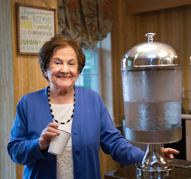 A resident standing at a water cooler smiling into the camera