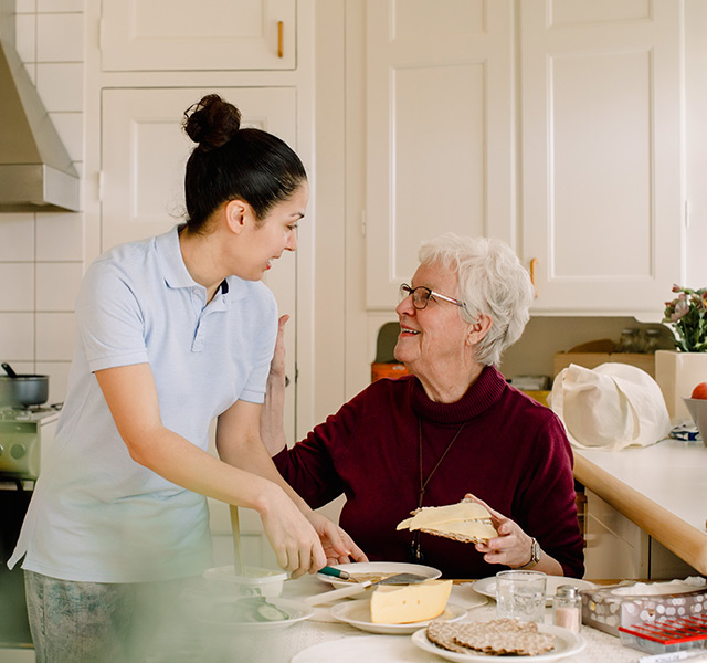 A caregiver is cutting up food for a resident.