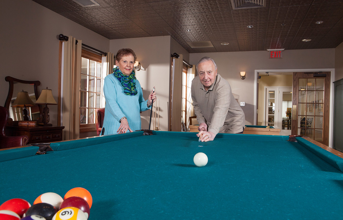 Two residents are playing a game of pool.
