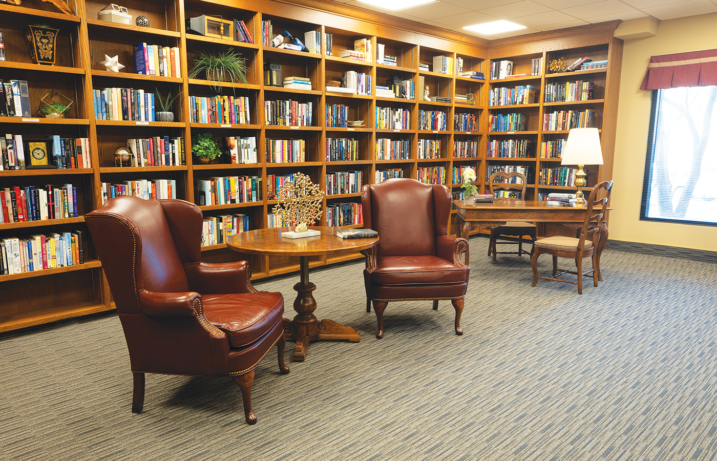 two chairs in front of large bookshelf within library