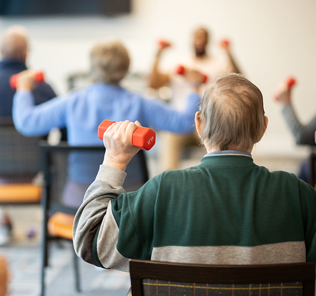A person lifting weights in a chair fitness class.