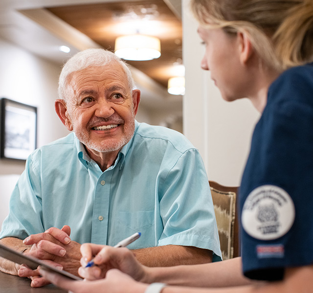 A resident sitting and chatting with a caregiver