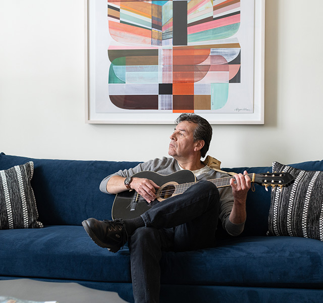 A resident on the couch playing guitar.