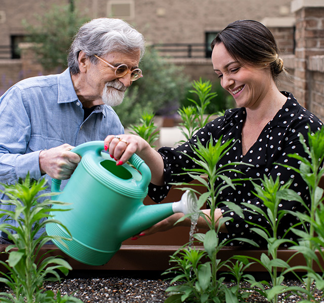 A person helping a resident water plants.