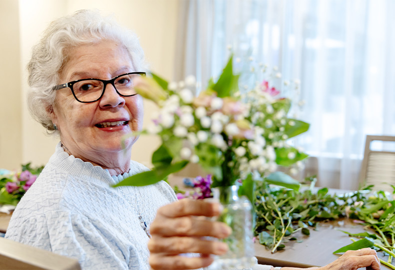 A person holding up a vase of flowers.