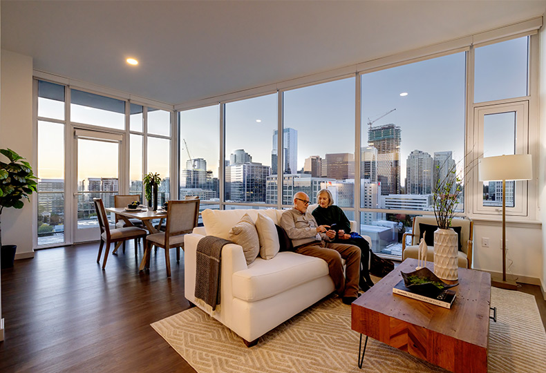 Two people sitting on a couch in their apartment.