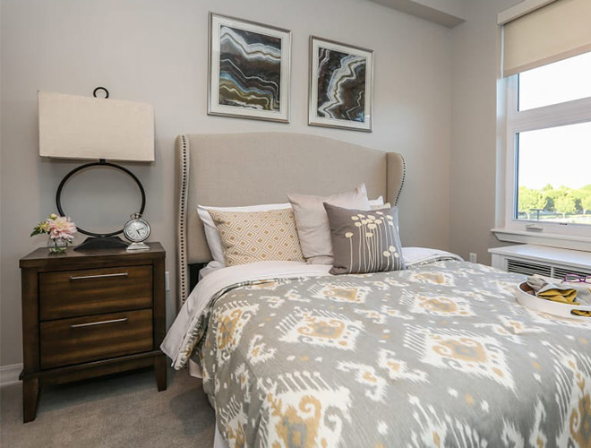 Furnished bedroom with bed, seating area, and soft lighting.