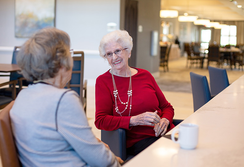 Residents sitting in dining room enjoying coffee.