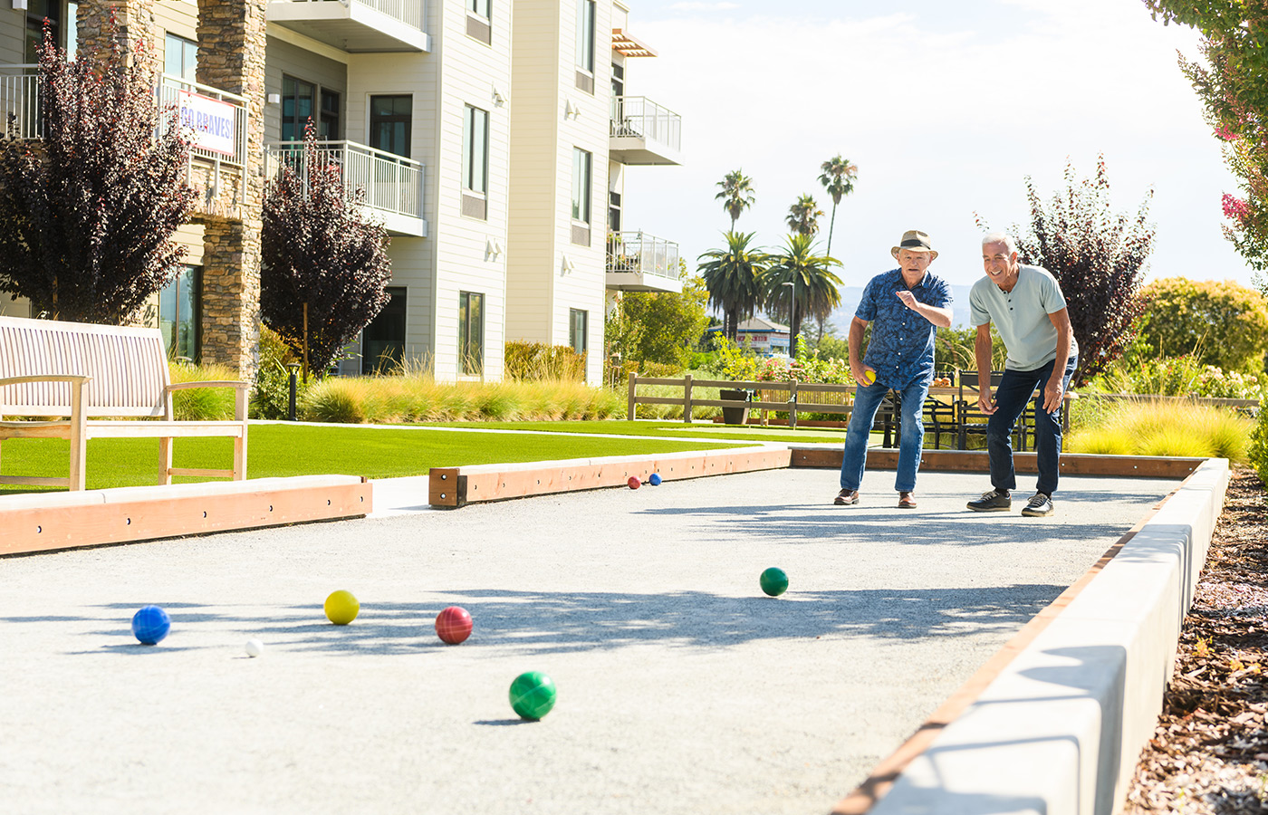 Two men playing bocce ball outside.