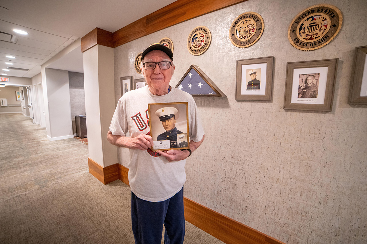 A veteran is holding a photo of when they served.