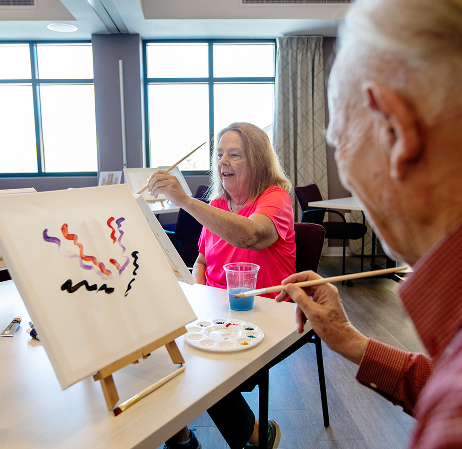 Two residents paining on canvases.