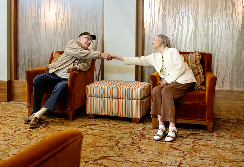A couple sitting in chairs holding each other's hands.