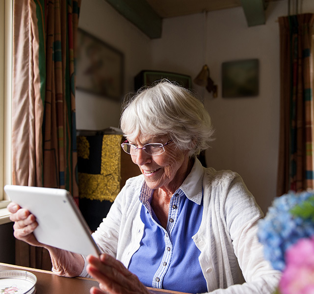 A resident looking at their tablet device smiling. 