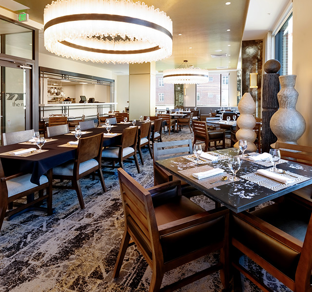A dining room with tables set for dinner.