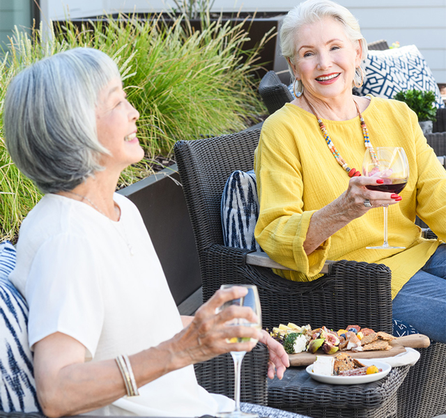 Two friends enjoying a glass of wine and plate of appetizers on the patio.