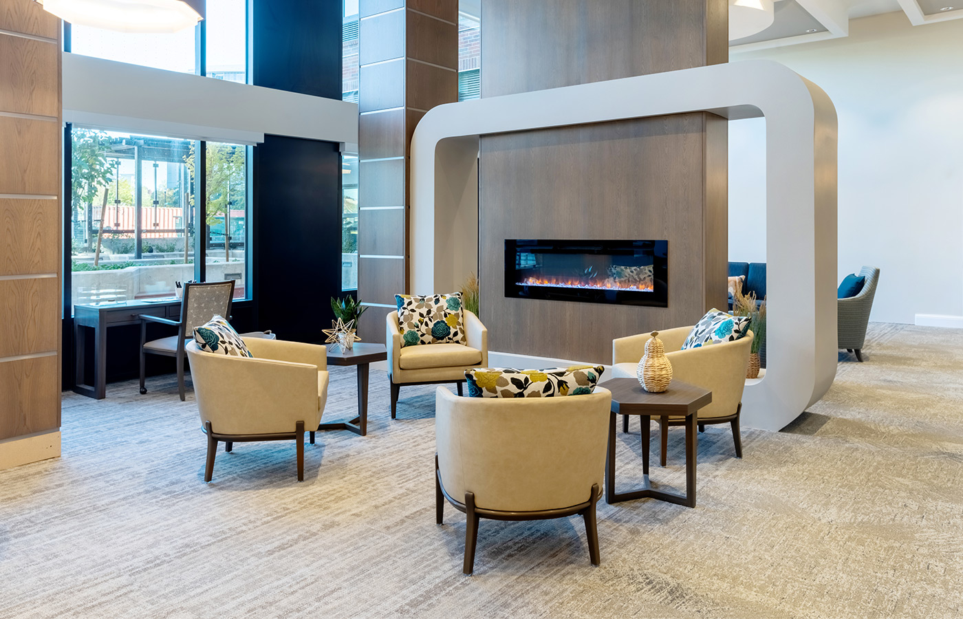 The memory care lounge area with seating and a fireplace.