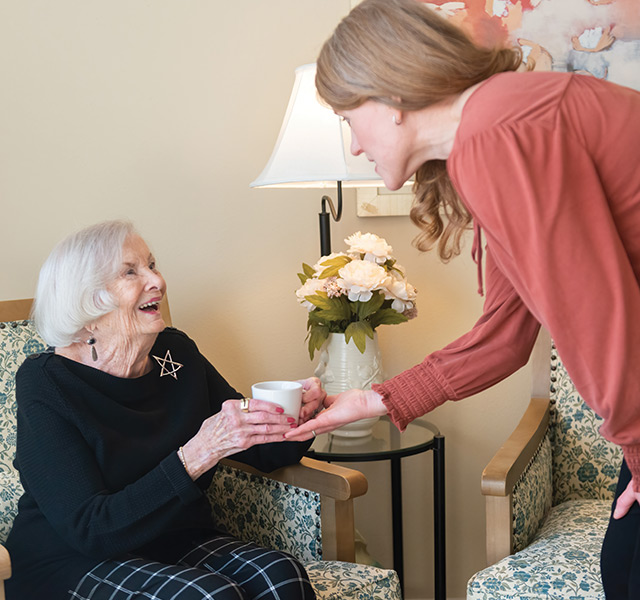 A person handing coffee to a resident.