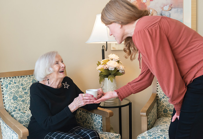 A person handing coffee to a resident.