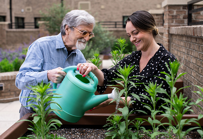 A person helping a resident water plants.