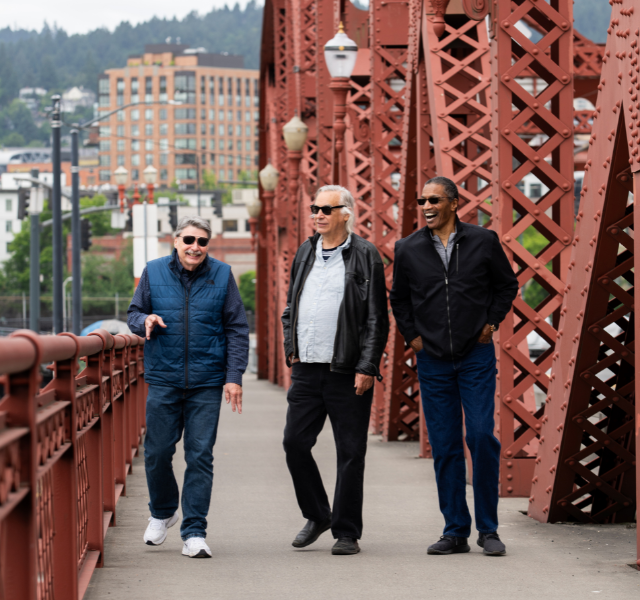 Three people walking across a bridge near Portland.
