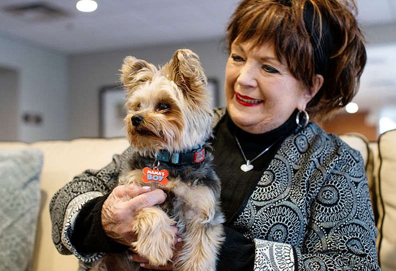 A resident is holding a small dog.